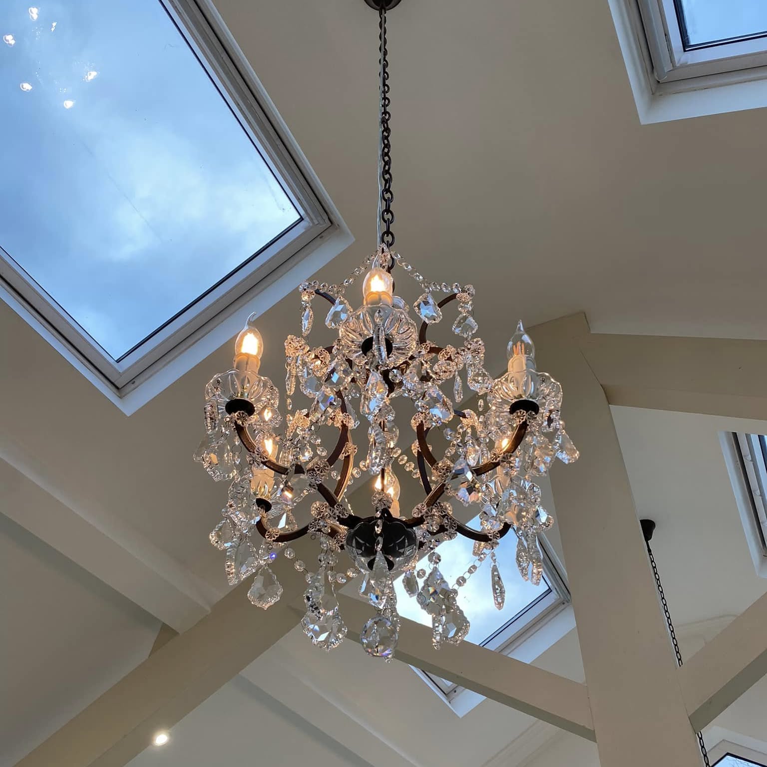 Chandelier hung between skylights in a vaulted ceiling